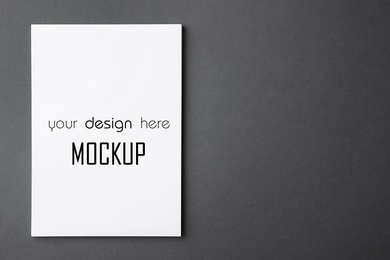 Paper sheet with text Mockup Your Design Here on dark grey background, top view