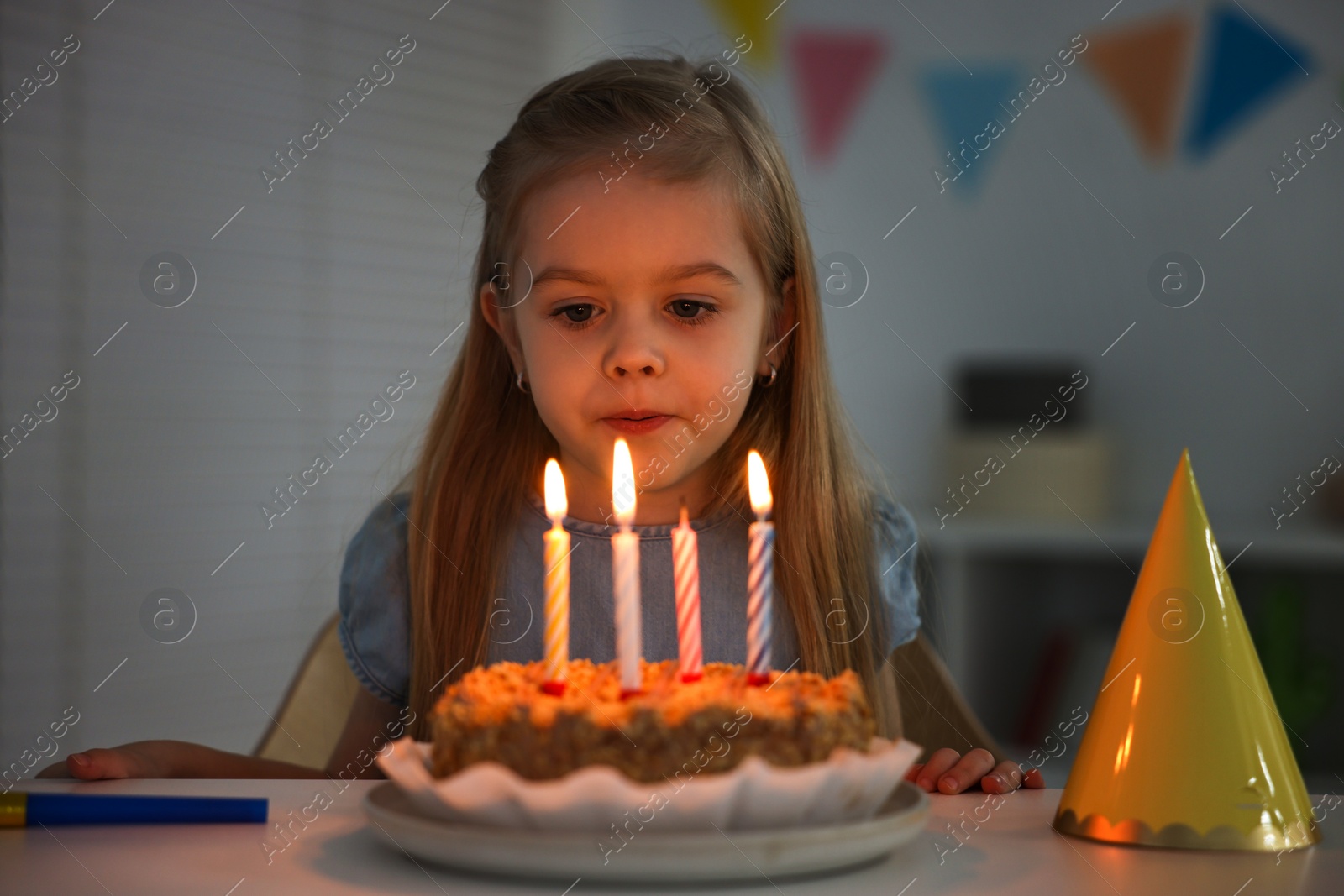 Photo of Cute girl with birthday cake at table indoors