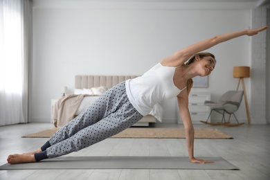 Young woman doing gymnastics on floor at home. Morning fitness