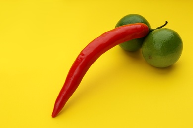 Chili pepper and limes symbolizing male sexual organ on yellow background. Potency problem