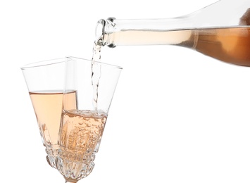 Photo of Pouring rose champagne from bottle into glass on white background