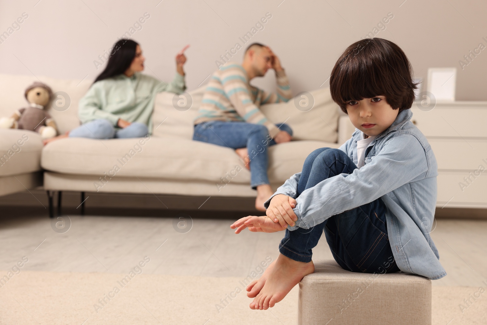 Photo of Couple arguing at home, focus on their upset child