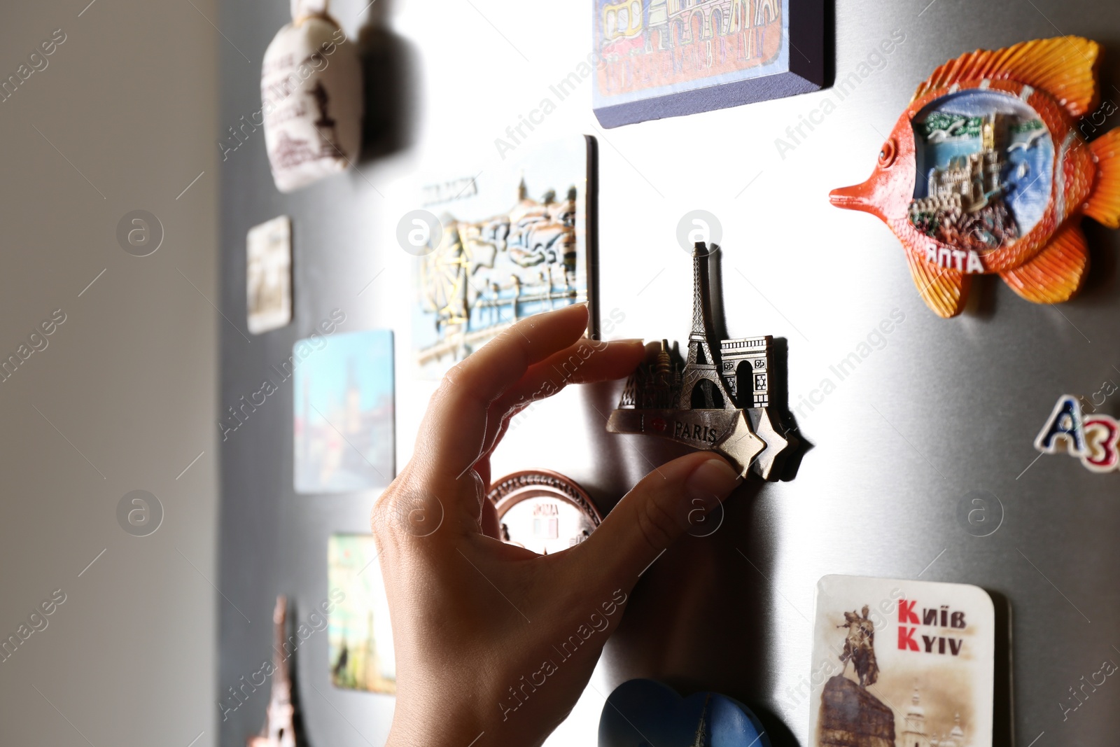 Photo of MYKOLAIV, UKRAINE - DECEMBER 25, 2018: Woman putting magnet on fridge door, closeup