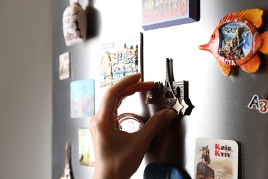 Photo of MYKOLAIV, UKRAINE - DECEMBER 25, 2018: Woman putting magnet on fridge door, closeup