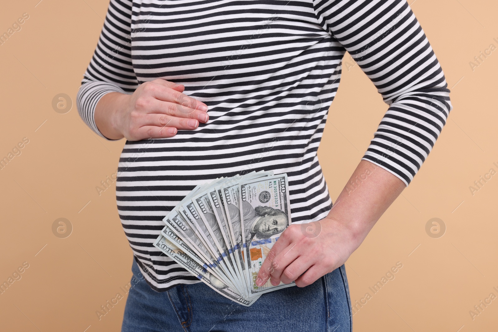 Photo of Surrogate mother. Pregnant woman with dollar banknotes on beige background, closeup