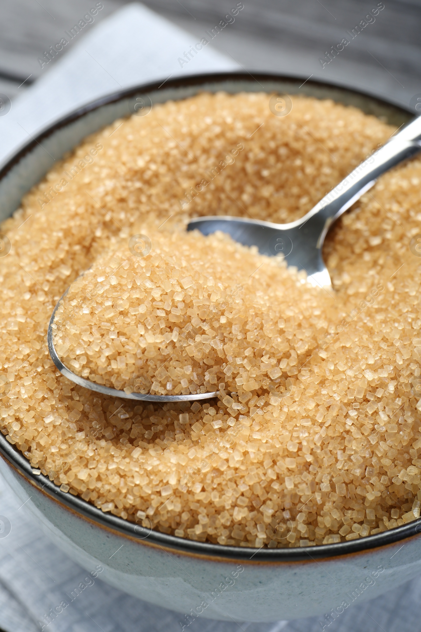 Photo of Brown sugar in bowl and spoon on table, closeup