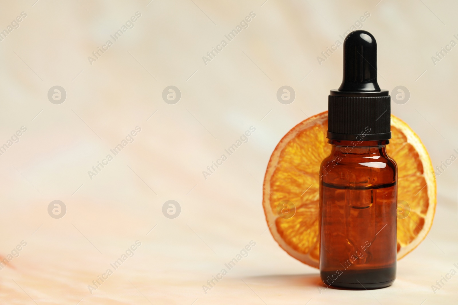 Photo of Bottle of organic cosmetic product and dried orange slice on pink marbled background, space for text