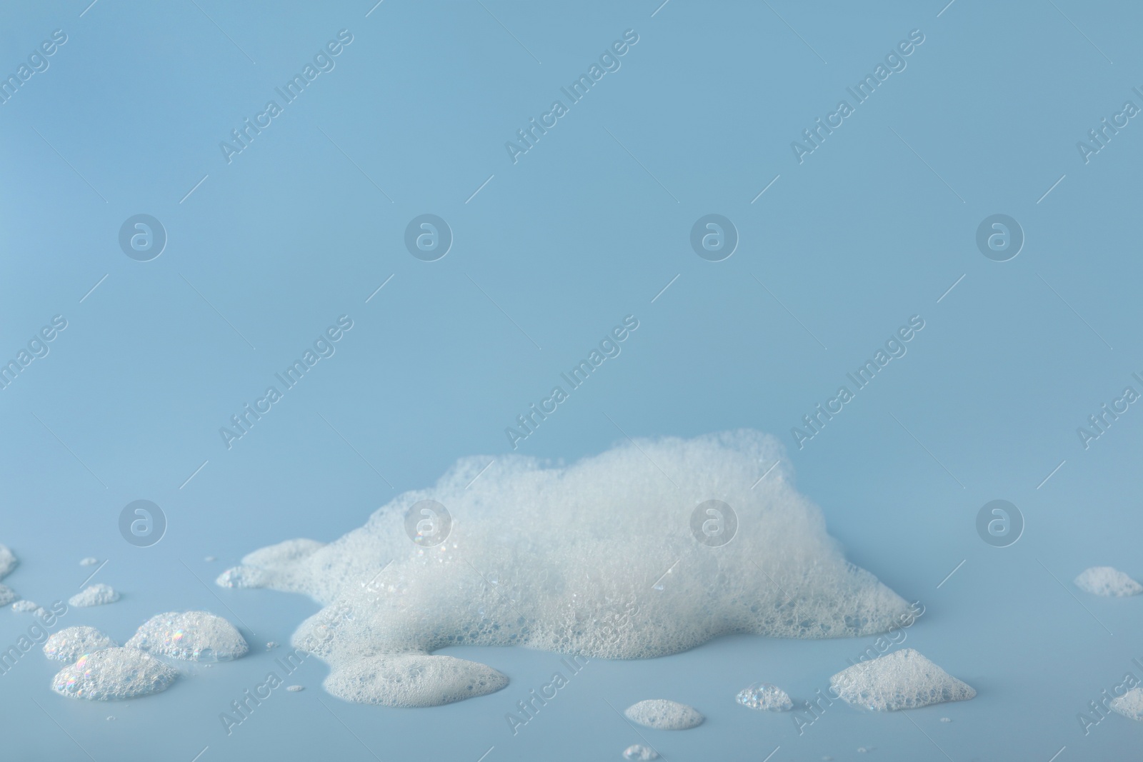 Photo of Fluffy bath foam on light blue background