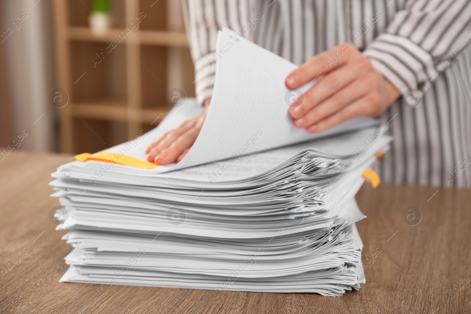 Photo of Woman stacking documents at wooden table indoors, closeup