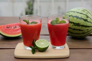 Photo of Glasses of delicious watermelon smoothie with mint and lime on wooden table