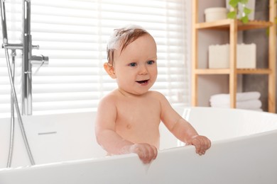 Cute little baby bathing in tub at home