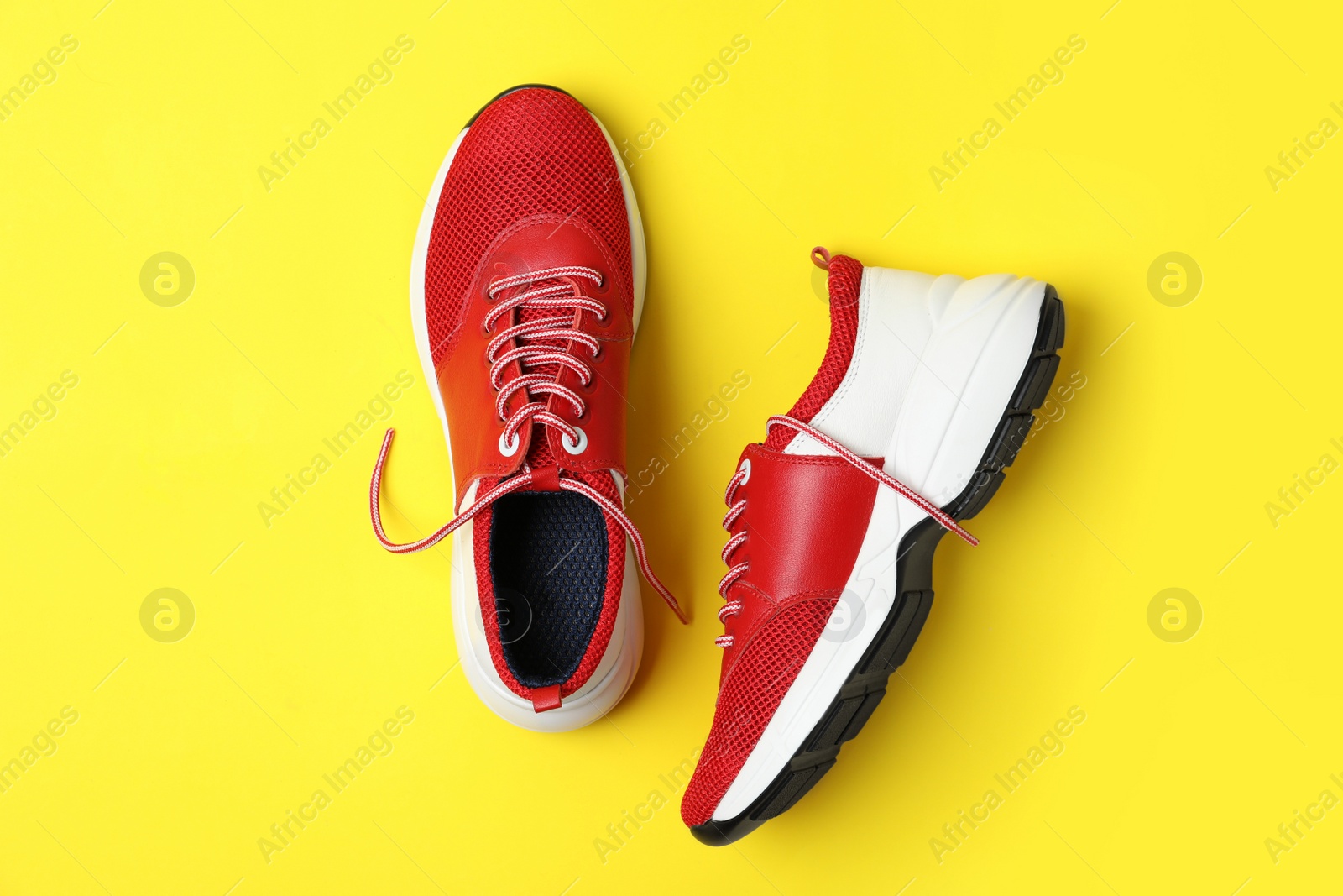 Photo of Stylish red sneakers on yellow background, flat lay