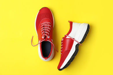 Photo of Stylish red sneakers on yellow background, flat lay