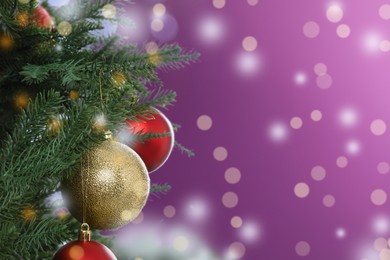 Image of Beautiful Christmas tree with bright baubles against blurred lights on violet background, closeup. Space for text