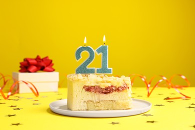 Photo of Coming of age party - 21st birthday. Delicious cake with number shaped candles on yellow background