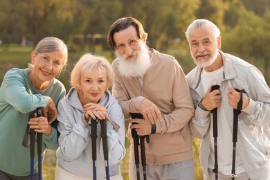 Photo of Senior men and women with Nordic walking poles outdoors