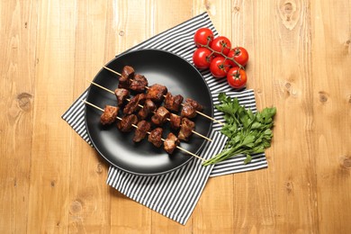 Photo of Delicious shish kebabs with vegetables on wooden table, flat lay