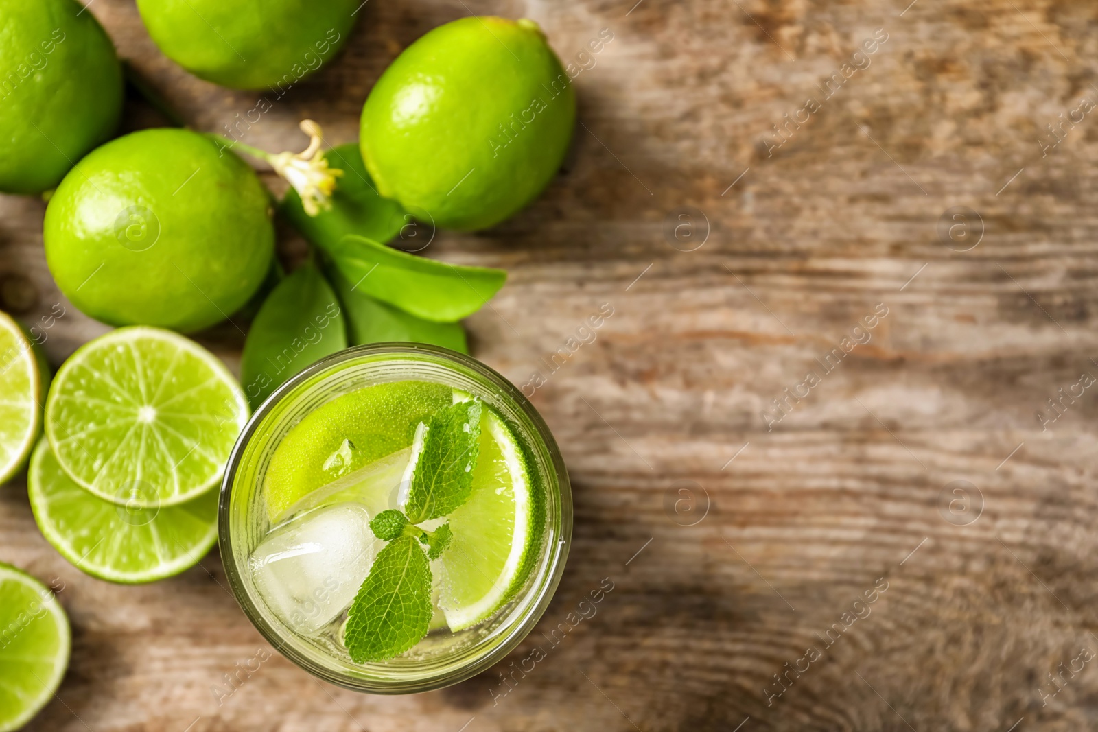 Photo of Refreshing lime beverage and ingredients on wooden background, top view