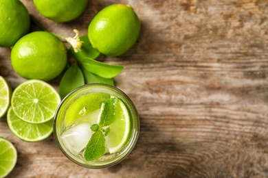 Photo of Refreshing lime beverage and ingredients on wooden background, top view