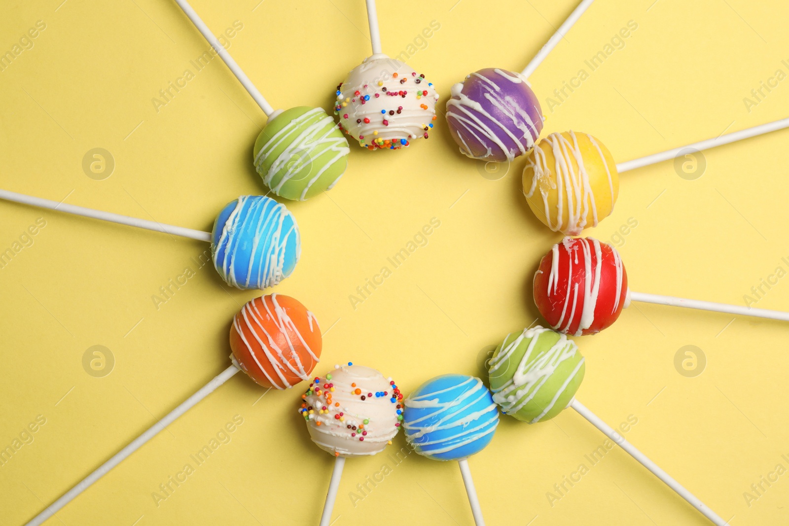 Photo of Frame made of bright delicious cake pops on color background, flat lay. Space for text