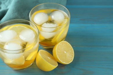 Photo of Delicious cocktails with lemon and ice balls on light blue wooden table, space for text