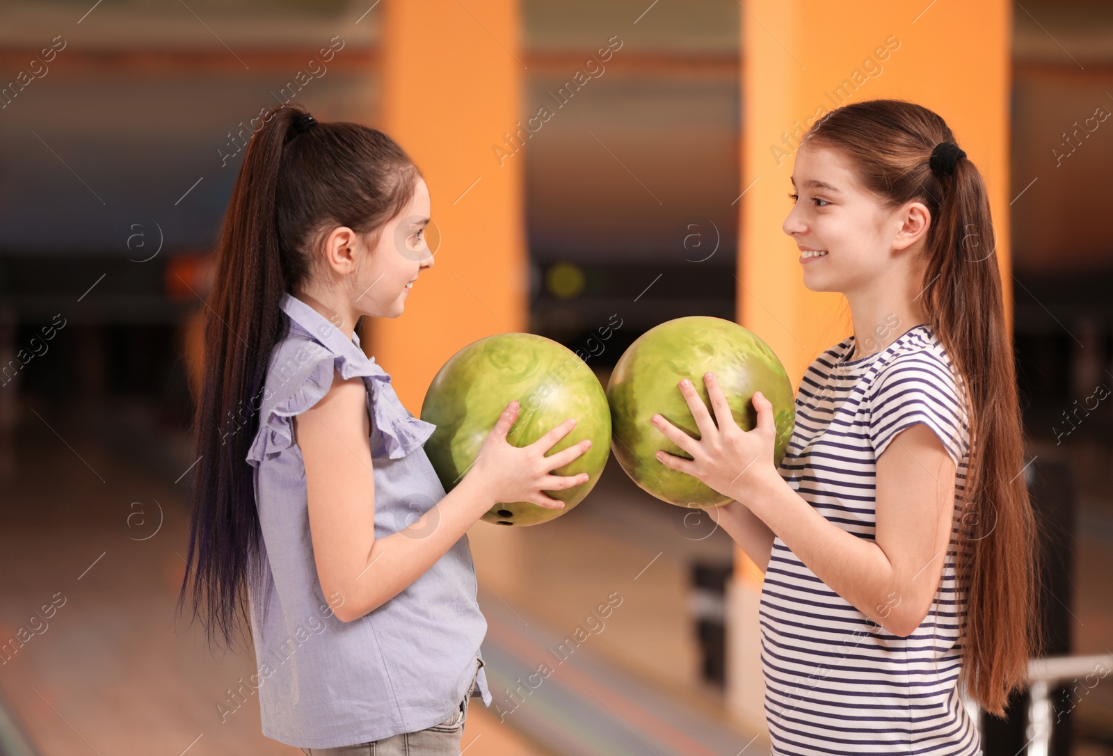 Photo of Happy girls with balls in bowling club