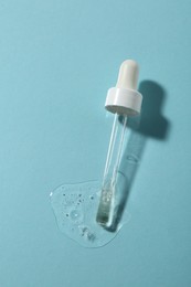 Photo of Pipette with cosmetic serum on light blue background, top view