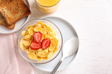 Flat lay composition with cornflakes and strawberries on white wooden table. Healthy breakfast