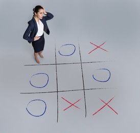 Image of Young woman and illustration of tic-tac-toe game on grey background, above view. Business strategy concept 