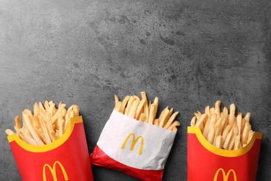 Photo of MYKOLAIV, UKRAINE - AUGUST 12, 2021: Small and big portions of McDonald's French fries on grey table, flat lay. Space for text