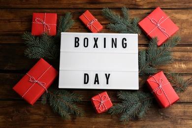 Photo of Lightbox with phrase BOXING DAY and Christmas decorations on wooden background, flat lay