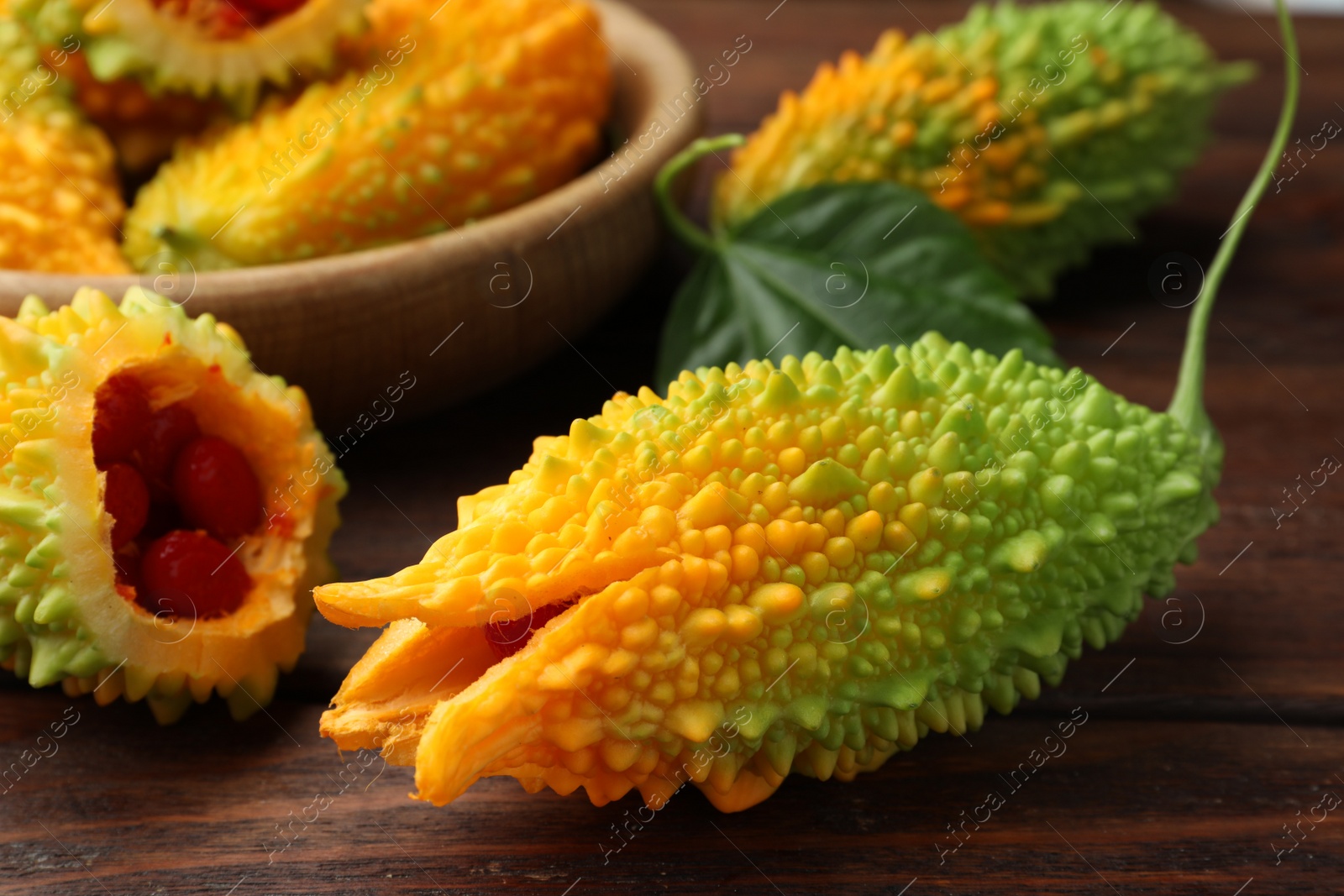 Photo of Fresh bitter melons on wooden table, closeup