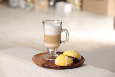 Aromatic latte macchiato in glass and cookies on white table against blurred background