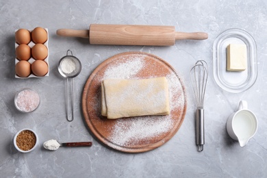 Flat lay composition with puff pastry dough and ingredients on grey table