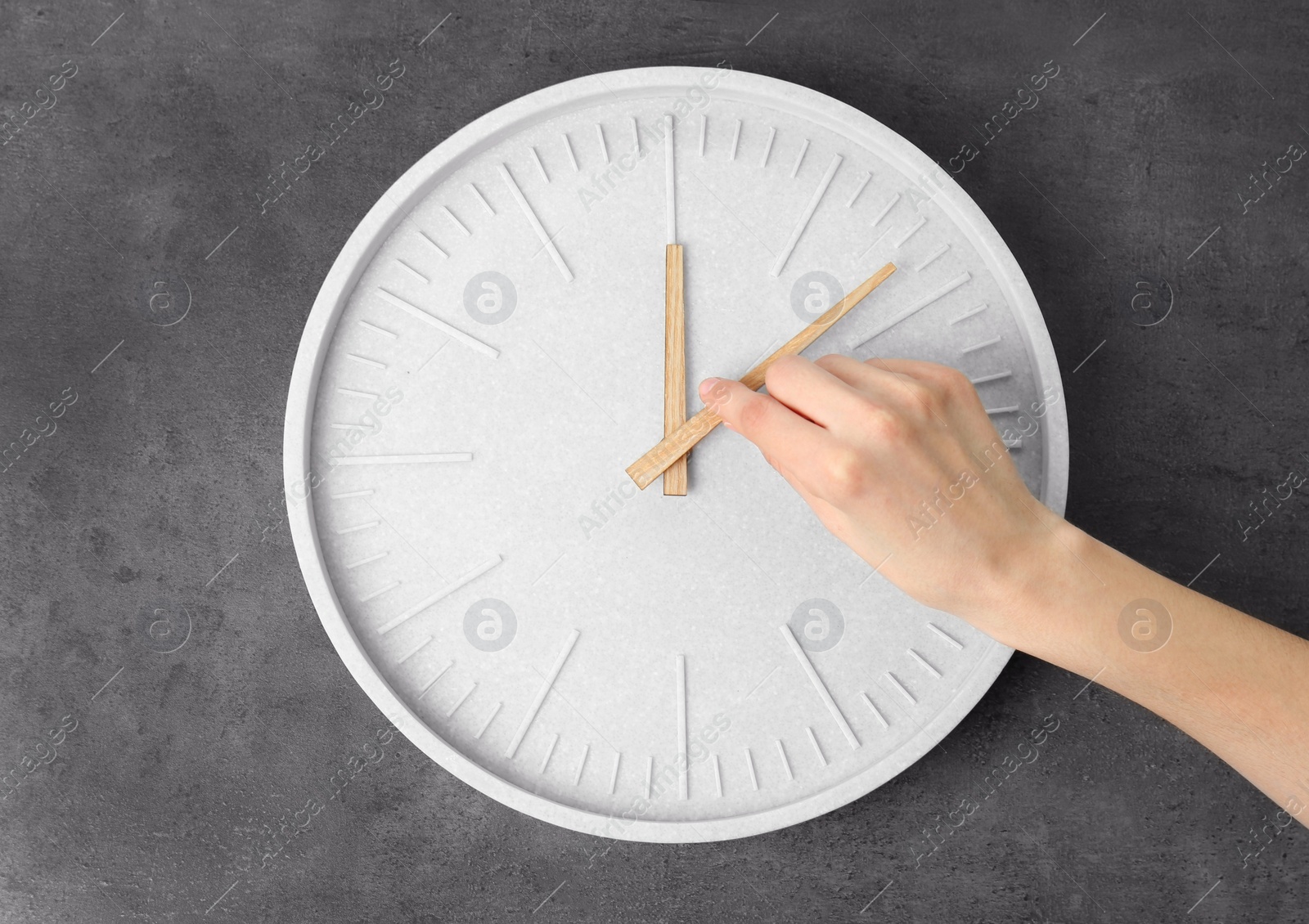 Photo of Woman changing time on big wall clock