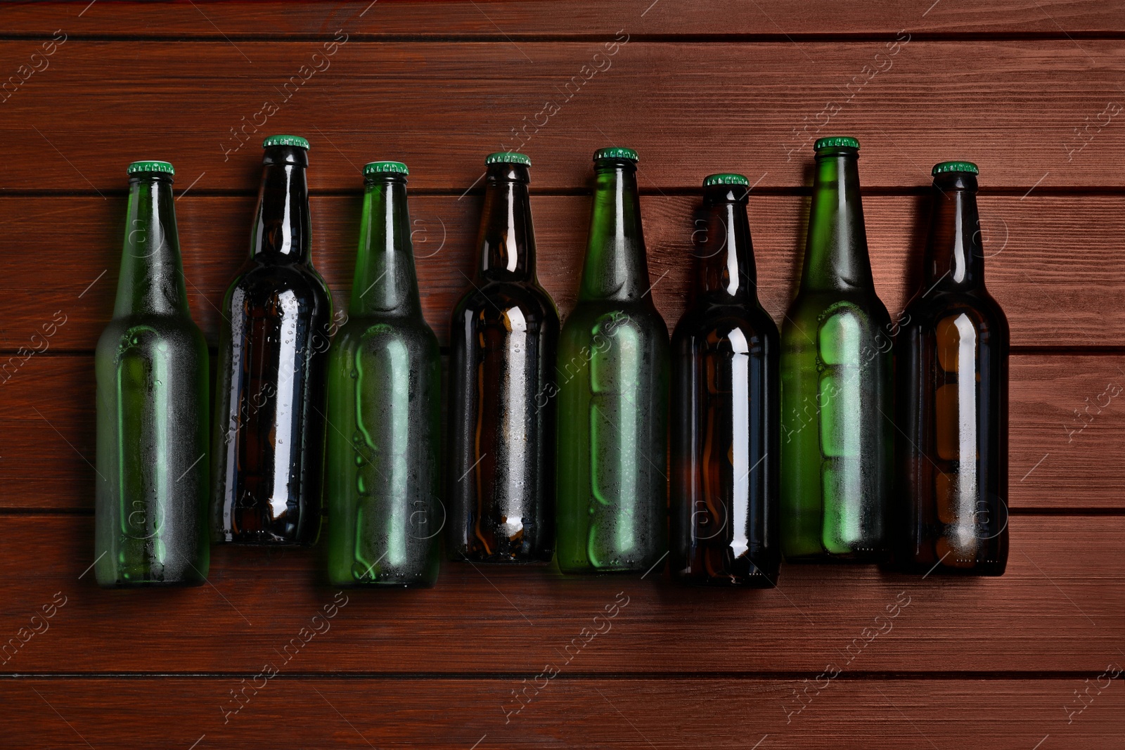 Photo of Glass bottles of beer on wooden background, flat lay