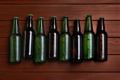 Photo of Glass bottles of beer on wooden background, flat lay
