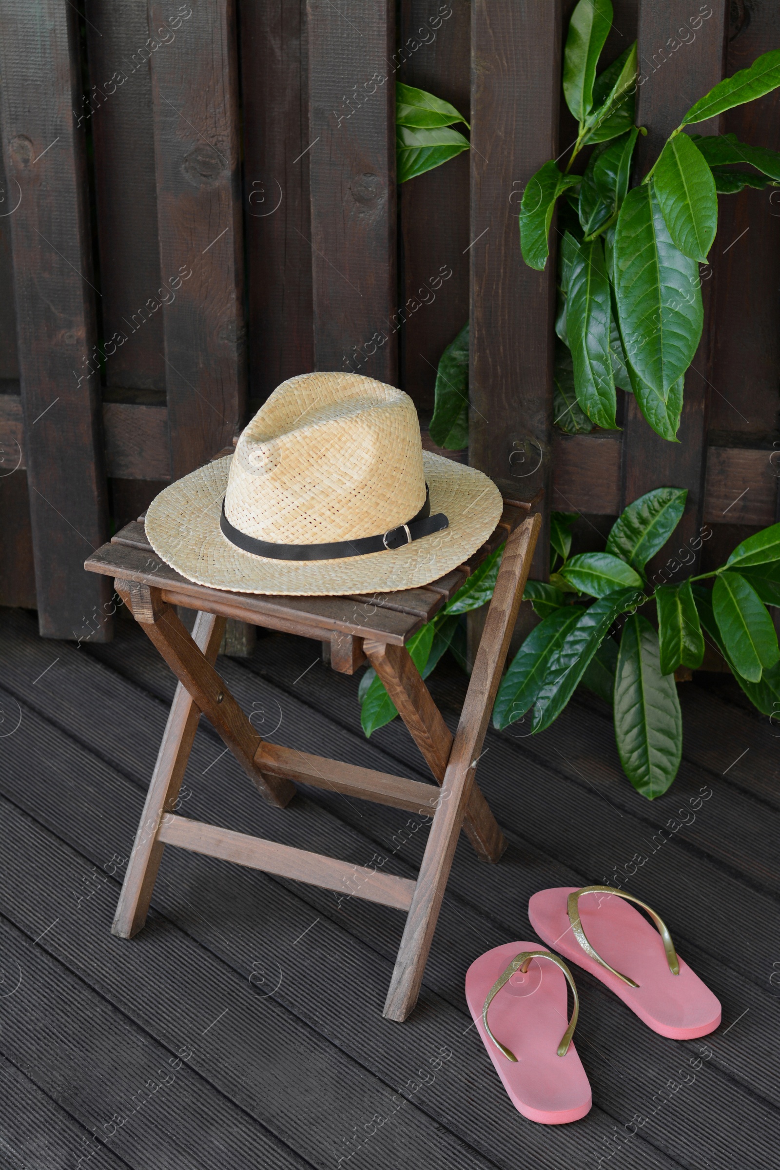 Photo of Stylish hat and flip flops near wooden fence. Beach accessories