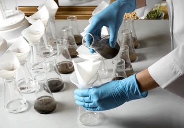 Photo of Scientist filtering soil samples at table, closeup. Laboratory analysis