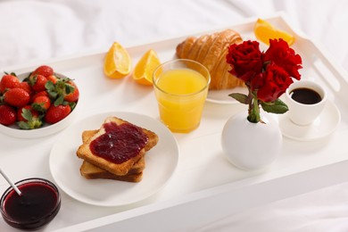 Photo of Tray with delicious breakfast on bed, closeup
