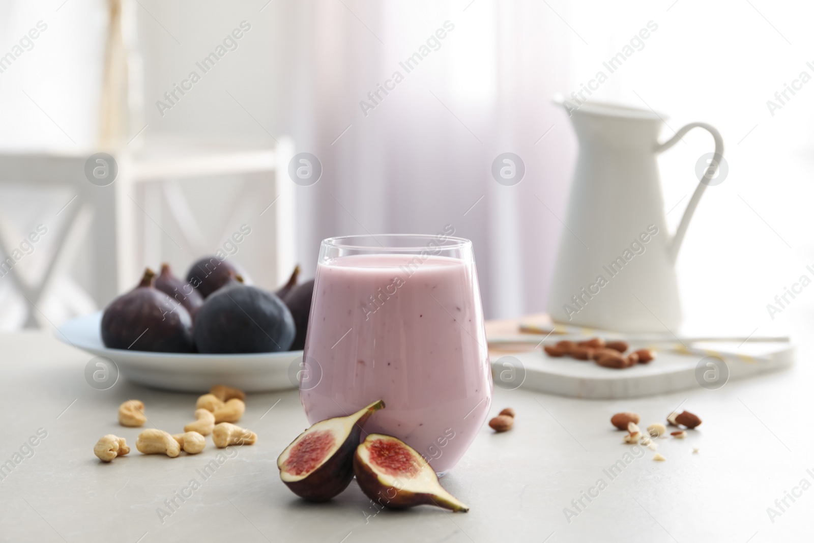 Photo of Delicious fig smoothie in glass on light table