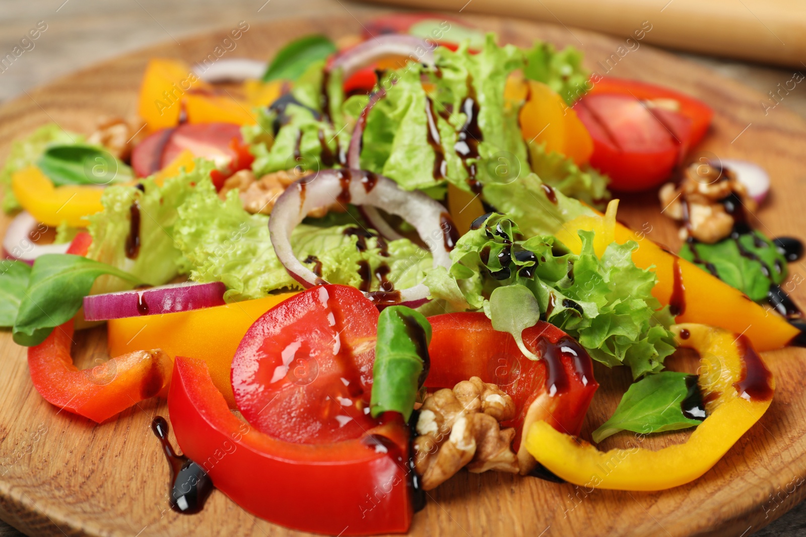 Photo of Fresh vegetable salad with balsamic vinegar on wooden plate, closeup