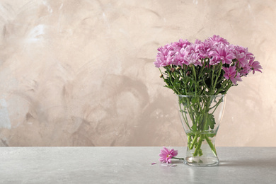 Beautiful chrysanthemum flowers in glass vase on table. Space for text