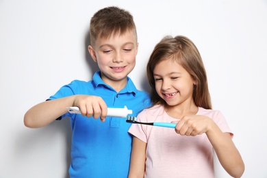 Photo of Cute children with toothbrush and paste on white background