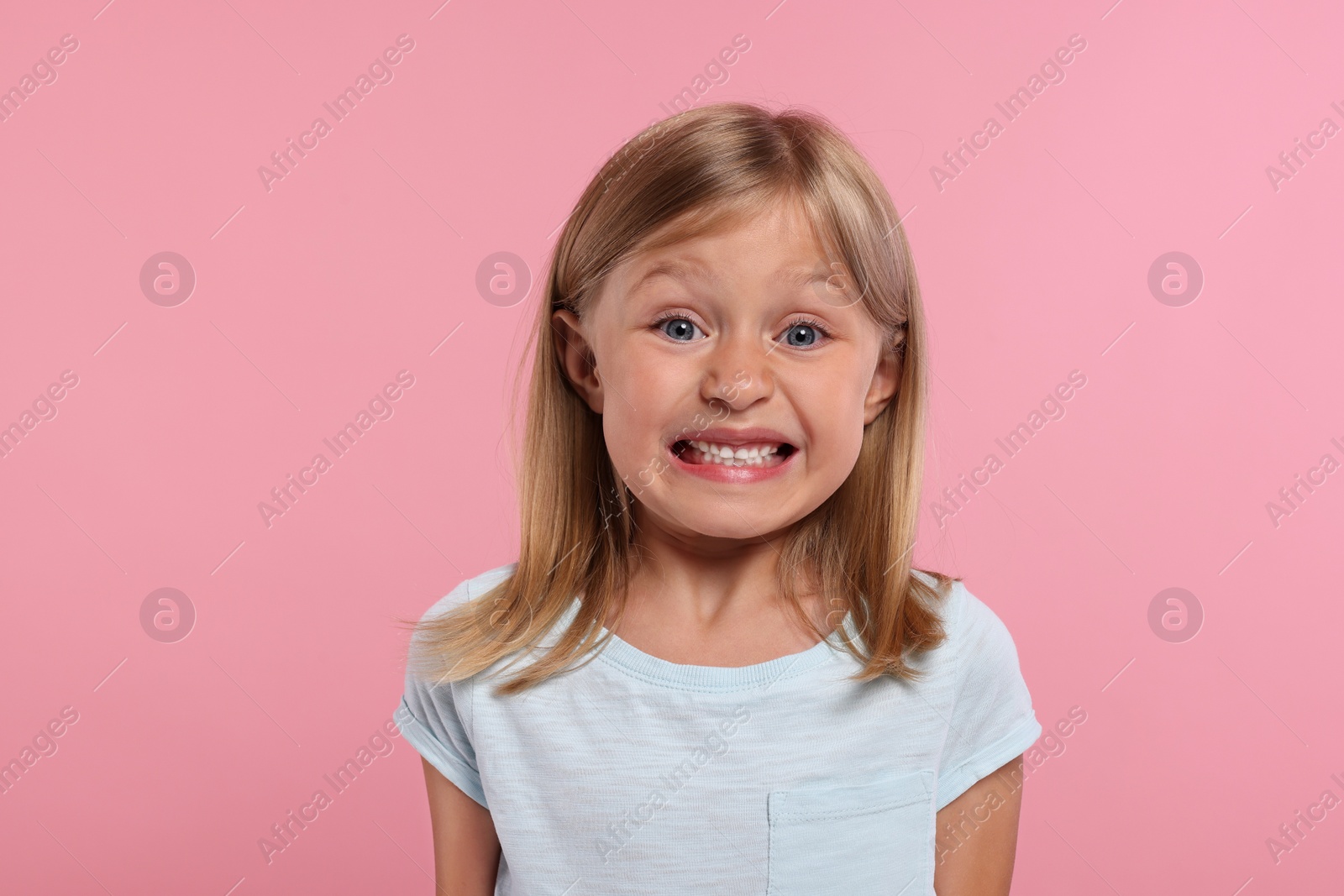 Photo of Embarrassment. Emotional little girl on pink background