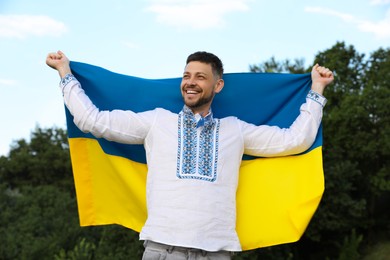 Man in vyshyvanka with flag of Ukraine outdoors