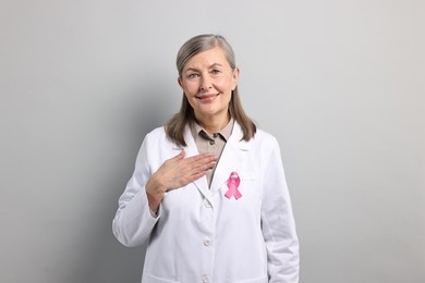 Photo of Mammologist with pink ribbon on gray background. Breast cancer awareness