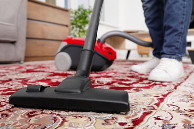 Man cleaning carpet with vacuum cleaner at home, closeup