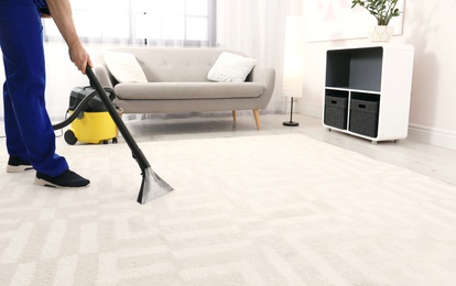 Photo of Man removing dirt from carpet with vacuum cleaner indoors, closeup. Space for text