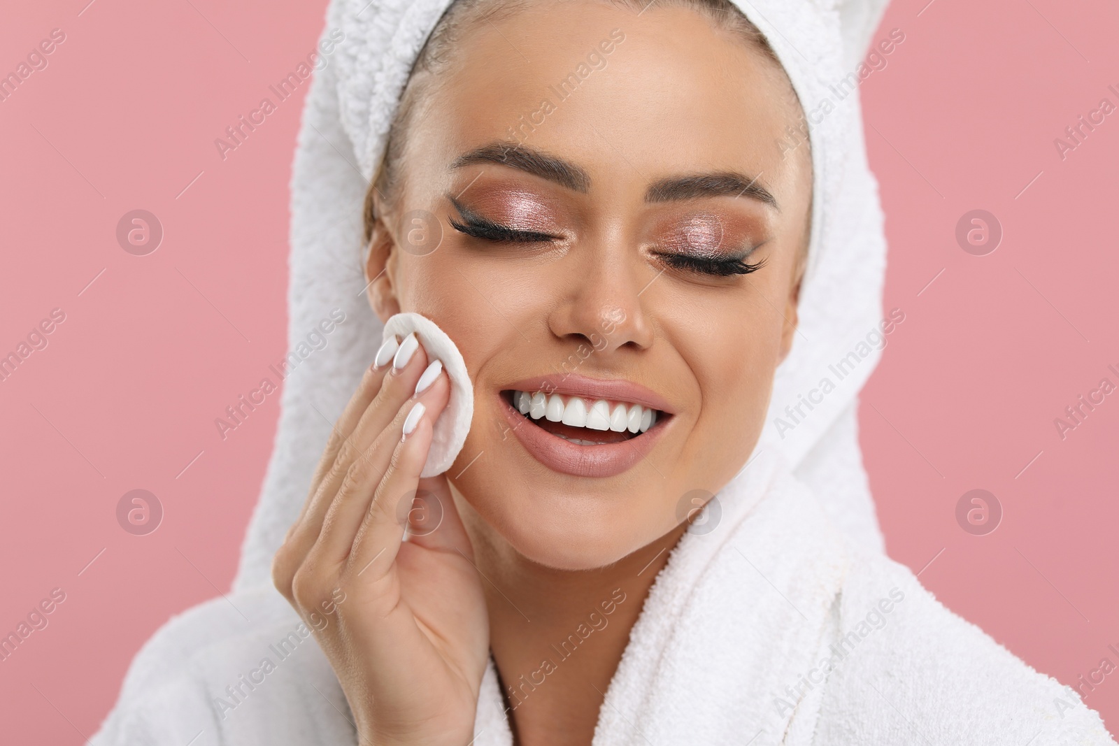 Photo of Beautiful woman removing makeup with cotton pad on pink background